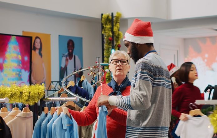 Clothing store worker helping woman